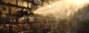 a powerful pressure washer blasting away grime and dirt from a weathered brick wall.