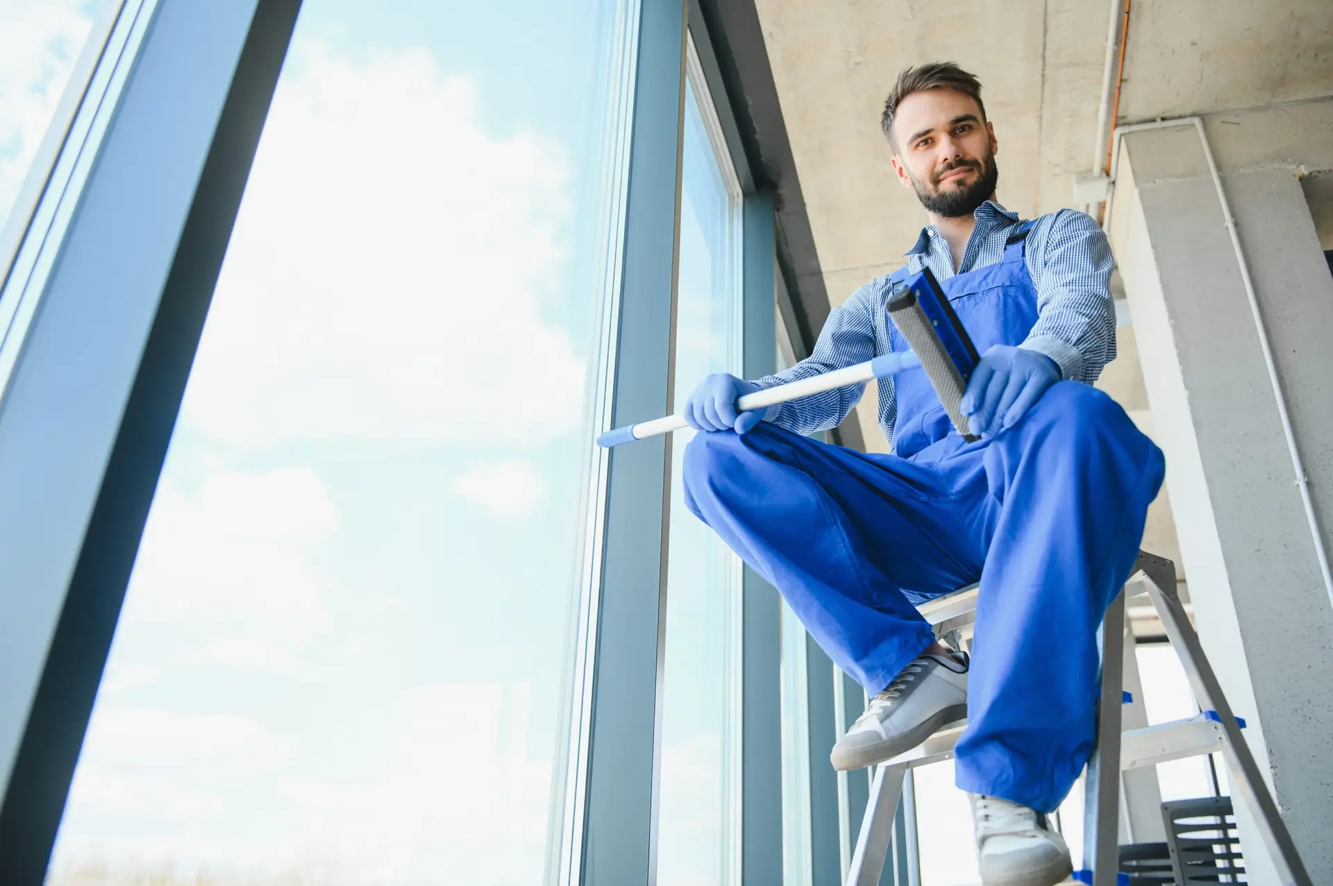 alliance window cleaning Brisbane team member sitting on a ladder with window cleaning equipment