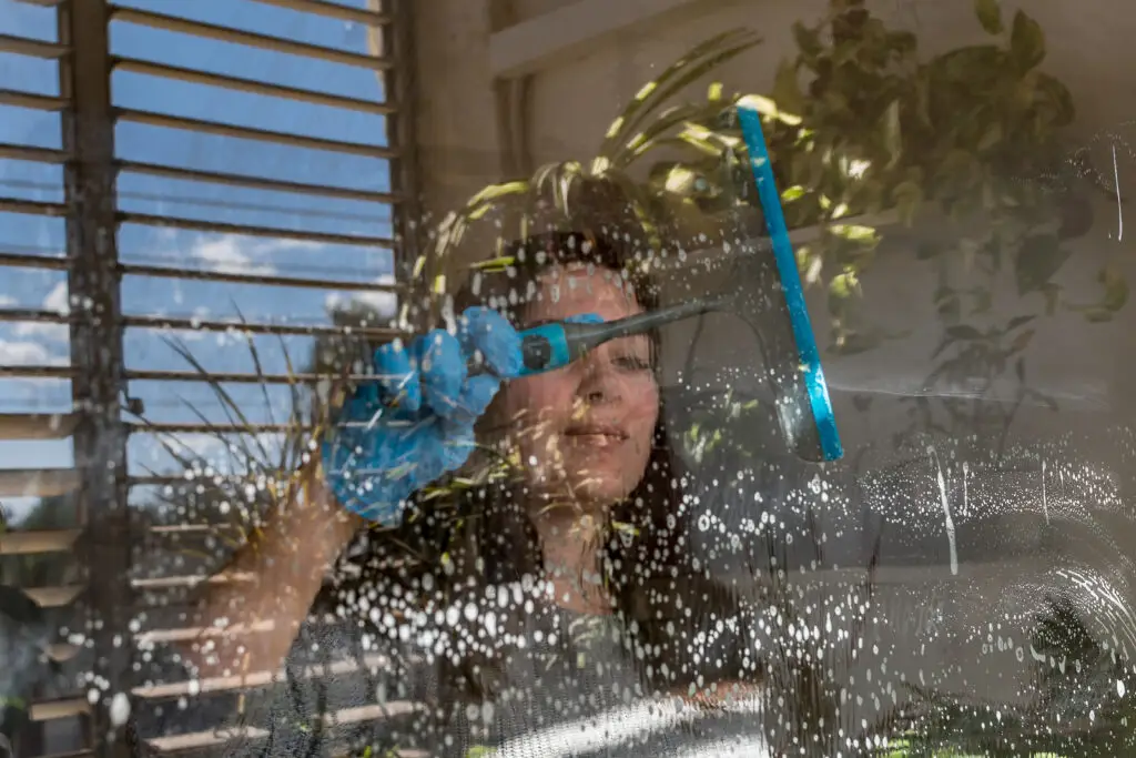 young female cleaning window in perth property